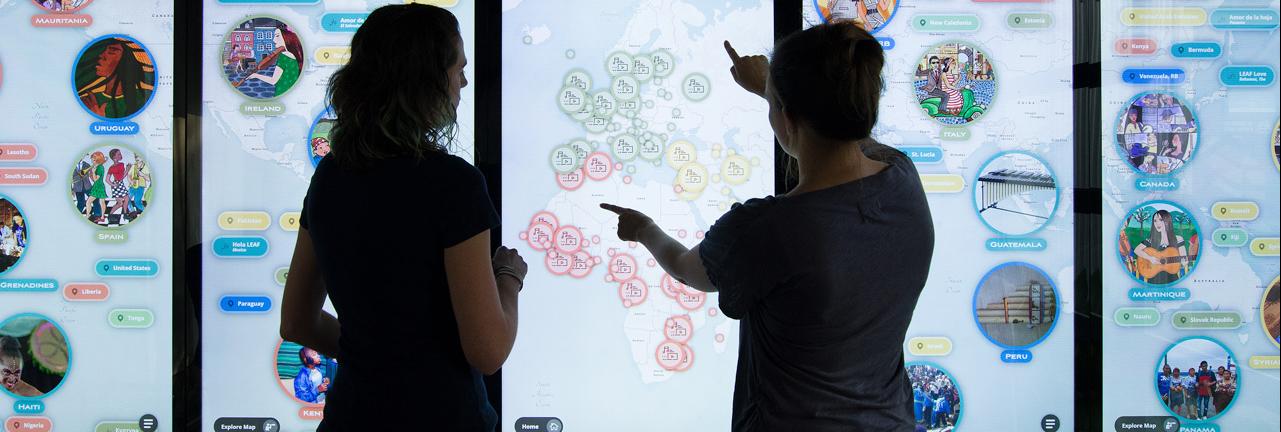 Two women touching screen that is showing a map
