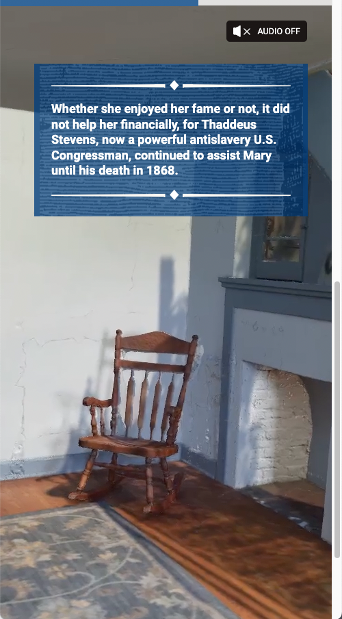 Screenshot of a rocking chair near a fireplace in Mary's stone house. Text reads - Whether she enjoyed her fame or not, it did not help her financially. for Thaddeus Stevens, now a powerful antislavery U.S. Congressman, continued to assist Mary until his death in 1868.