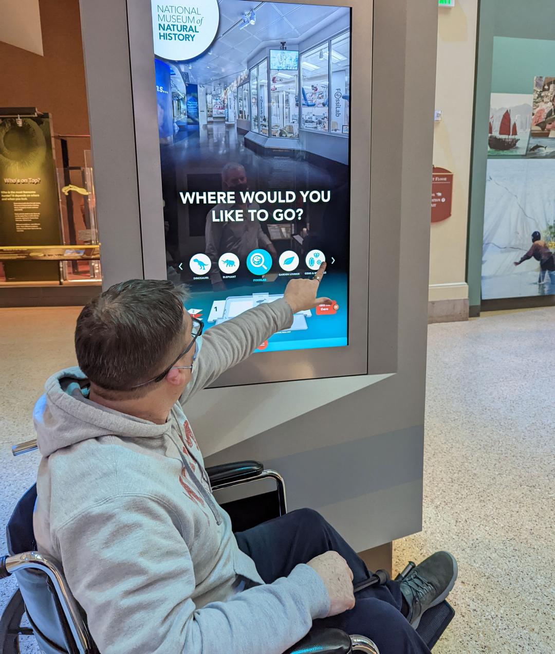 a man in a wheelchair is in front of a touchscreen kiosk